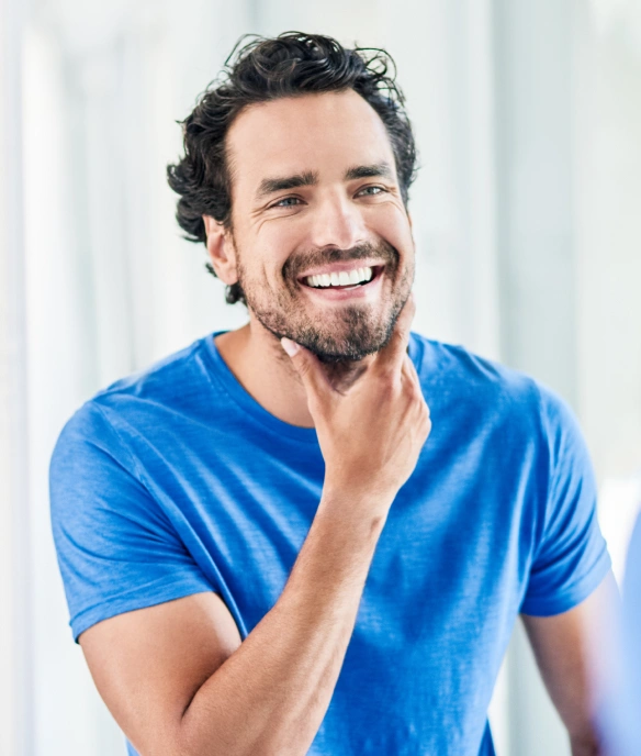 Man in blue shirt smiling at camera in bright dental office setting.