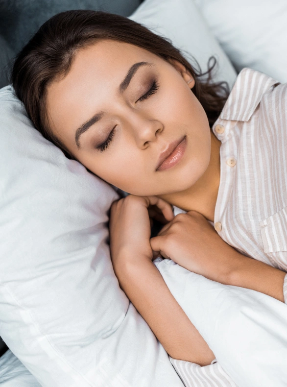 Woman peacefully sleeping on white pillow and bedding in comfortable bedroom setting.